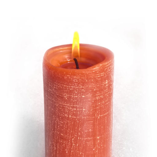 Photo of a lit red candle with a yellow flame and textured sides showing fine horizontal and vertical lines that have a bit of white coloring to accentuate the textured appearance, set onto what appears to be a snow-covered surface